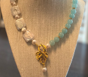 a necklace with beads and a gold leaf charm
