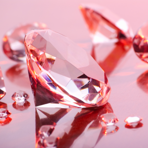 a pink diamond surrounded by diamonds on a reflective surface