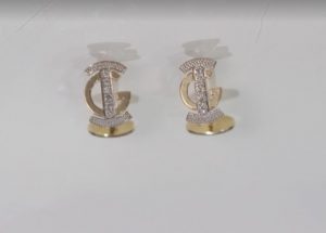 two gold and diamond earrings on a white surface
