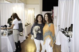 two women standing next to each other holding a dog