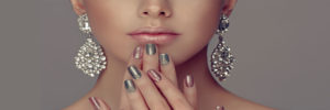 a woman with silver nail polish holding her hands to her face