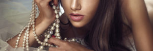 a woman with long brown hair wearing pearls