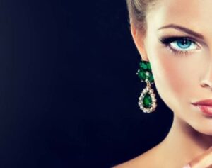 a woman with blue eyes wearing green earrings