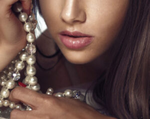 a woman holding a necklace with pearls on it