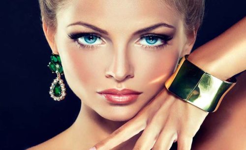 a beautiful woman with blue eyes wearing green jewelry