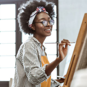 a woman with an afro painting on a canvas