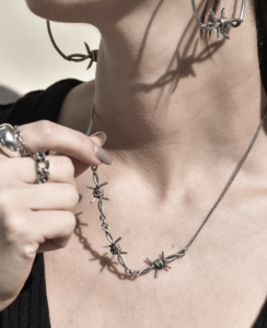 a woman wearing a necklace with barbed wire attached to it